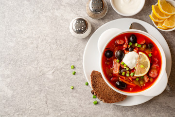Traditional Russian meat soup Solyanka in bowl on grey stone background. Top view. Copy space.