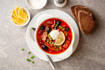 Traditional Russian meat soup Solyanka in bowl on grey stone background. Top view.