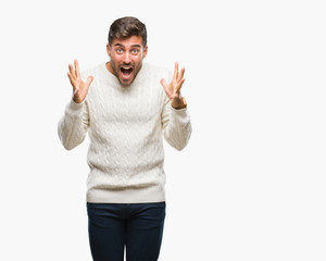 Naklejka premium Young handsome man wearing winter sweater over isolated background celebrating crazy and amazed for success with arms raised and open eyes screaming excited. Winner concept