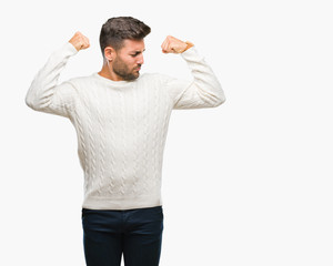Fototapeta premium Young handsome man wearing winter sweater over isolated background showing arms muscles smiling proud. Fitness concept.