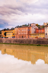 Fototapeta na wymiar Colorful old buildings on the bank of Arno river in Florence, Italy with reflection in water. Medieval architecture
