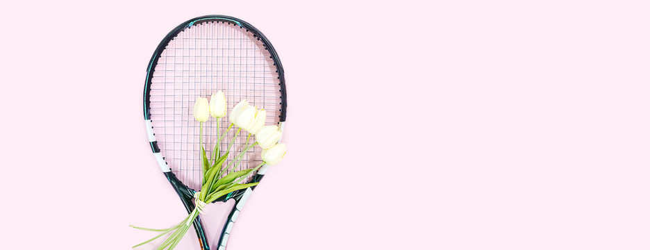 tennis love layout on pastel pink background with tennis racket with bouquet white tulips flowers. Women's Day March 8. Copy space. Valentine's day concept with tennis play. Flat lay, horizontal.