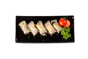Eggplant rolls with cheese, garlic and sesame on black plates with herbs and tomato. Top view and isolated on white background
