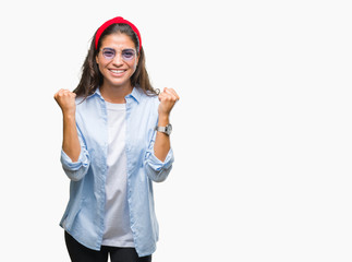 Fototapeta na wymiar Young beautiful arab woman wearing sunglasses over isolated background celebrating surprised and amazed for success with arms raised and open eyes. Winner concept.