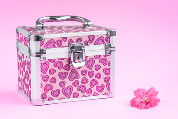 Pink jewelry box and pink flower isolated on pink background.