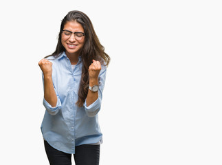 Young beautiful arab woman wearing glasses over isolated background very happy and excited doing winner gesture with arms raised, smiling and screaming for success. Celebration concept.