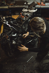 Fototapeta na wymiar beautiful girl with long hair in the garage repairing a motorcycle