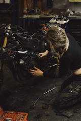 Naklejka na ściany i meble beautiful girl with long hair in the garage repairing a motorcycle
