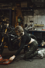 Obraz na płótnie Canvas beautiful girl with long hair in the garage repairing a motorcycle
