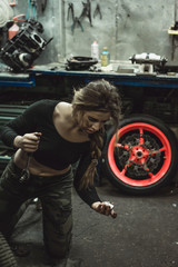 Obraz na płótnie Canvas beautiful girl with long hair in the garage repairing a motorcycle