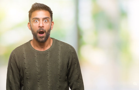 Adult hispanic man wearing winter sweater over isolated background afraid and shocked with surprise expression, fear and excited face.