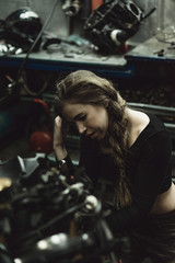 Obraz na płótnie Canvas beautiful girl with long hair in the garage repairing a motorcycle