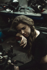 Obraz na płótnie Canvas beautiful girl with long hair in the garage repairing a motorcycle