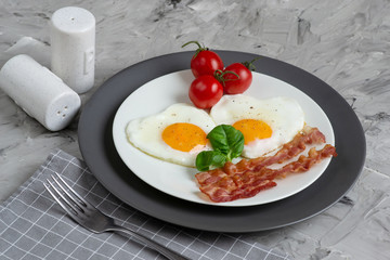 Tasty Fried Egg in the Shape of a Heart Served on a White Plate with Bacon Tomato Basil Pepper Gray Background Valentine Day Breakfast