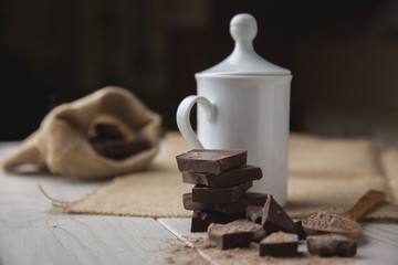 Taza con chocolate caliente en invierno y algunos trozos de chocolate puro