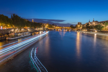 Fototapeta na wymiar Trainées de lumière sur la Seine à Paris de nuit