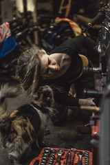 Plakat beautiful girl with long hair in the garage repairing a motorcycle