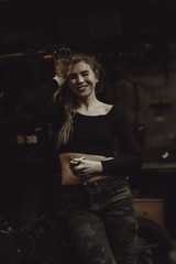 Obraz na płótnie Canvas beautiful girl with long hair in the garage repairing a motorcycle