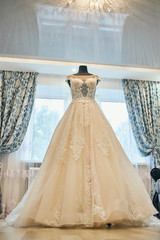 beautiful wedding dress hanging in the room, woman getting ready before  ceremony