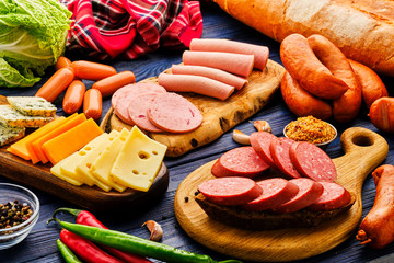 Smoked meat products on a wooden table. Sliced sausage. Sausage with different cheese on the table