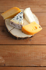 Cheese on wooden boards. Camembert, hard yellow cheese, dorblu on wooden stand. Top view