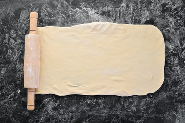 Background of the preparation of flour dough. rolling pin and flour on a black background. Top...