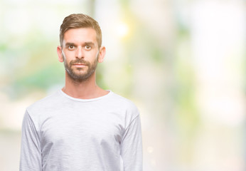 Naklejka premium Young handsome man over isolated background with serious expression on face. Simple and natural looking at the camera.
