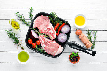Raw steak on the bone. Meat with spices and herbs. On a white wooden background. Top view. Free...
