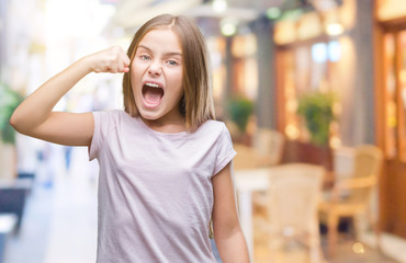 Young beautiful girl over isolated background angry and mad raising fist frustrated and furious while shouting with anger. Rage and aggressive concept.