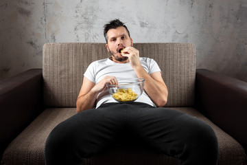The guy in the shirt is lying on the couch, eating chips and watching a sports channel. The concept...