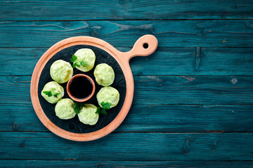 Hinkali with meat, spinach and soy sauce. On a wooden background. Top view. Free copy space.