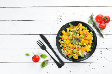 Salad of pumpkin, avocado and pumpkin seeds. On a white wooden background. Top view. Free space for your text.