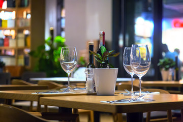 Bottle of wine in bottle and empty glasses in the evening cafeteria or restaurant.