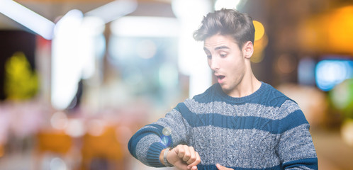 Young handsome man over isolated background Looking at the watch time worried, afraid of getting...