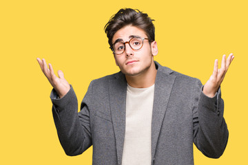Young business man wearing glasses over isolated background clueless and confused expression with...