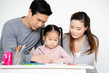 Asian Mom and Dad are teaching crayon skills to Daughters. To draw line. Write book on paper...