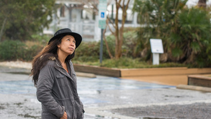 Asian woman with black hat and parka looking up in the air © David