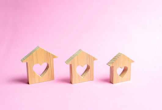 Houses with hearts inside on a pink background. The concept of finding a love nest. Affordable housing for young families and couples. Rental of houses and apartments by young people. Valentine's Day.