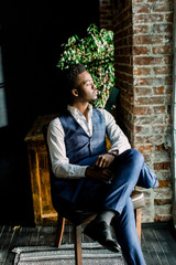 Obraz premium Close up portrait of handsome young male fashion model sitting by a window
