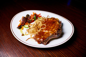Appetizing dish on a white plate stands on a wooden table, food, snack