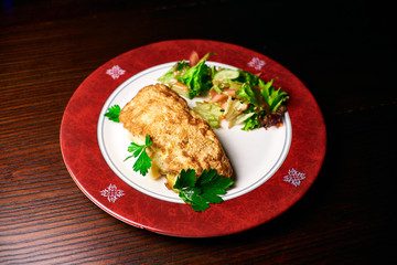 Appetizing dish on a white plate stands on a wooden table, food, snack