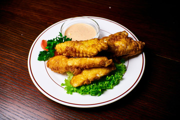 Appetizing dish on a white plate stands on a wooden table, food, snack