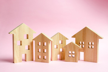 A lot of wooden houses on a pink background. The concept of the city or town. Investing in real...