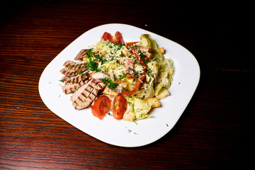 Appetizing dish on a white plate stands on a wooden table, food, snack