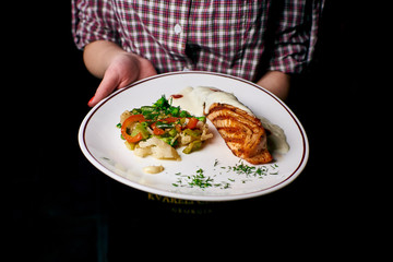 Appetizing dish on a white plate in the hands of the girl waiter, food, snack