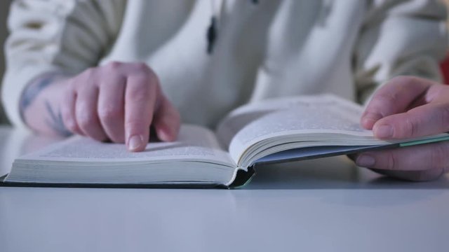 Hand and book: reading a book and holding your fingers along the lines. A woman's hand holds a book and moves her fingers along the page while reading. The reader of the book holds