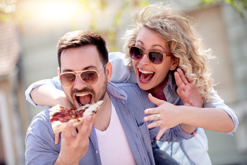 Couple eating pizza snack outdoors