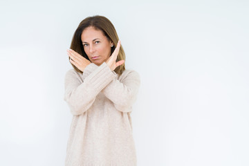 Beautiful middle age woman over isolated background Rejection expression crossing arms doing...