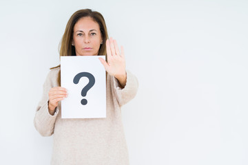 Middle age woman thinking and holding paper with question mark symbol over isolated background with open hand doing stop sign with serious and confident expression, defense gesture