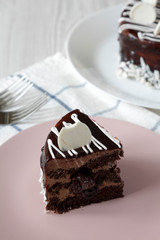 Piece of homemade chocolate cherry cake on a pink plate, side view. Close-up.